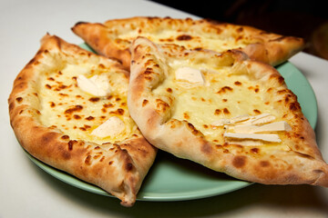 Ajarian traditional flatbread khachapuri or hachapuri with cheese and butter on a plate