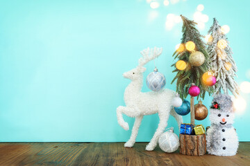 Image of christmas tree with decorations and white deer in front of pastel blue background