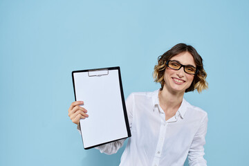 Business woman with documents in a folder on a blue background and in a light shirt glasses on her face