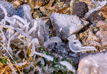 Bizarre ice shard in the riverbed, autumn grass covered with shiny beautiful ice in close proximity to the river; first autumn frosts and approaching winter concept