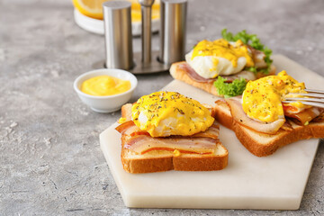 Board with tasty eggs Benedict on table