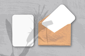 An envelope with two sheets of textured white paper on the gray background of the table. Mockup...