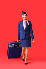 Beautiful stewardess with luggage on color background