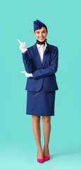 Beautiful stewardess pointing at something on color background