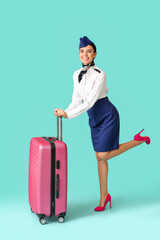 Beautiful stewardess with luggage on color background
