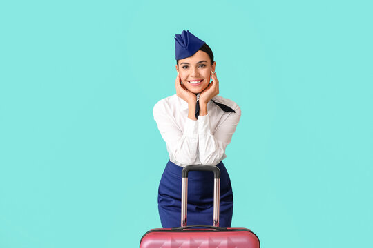 Beautiful stewardess with luggage on color background