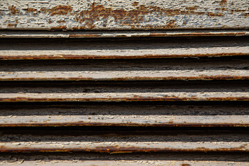 Rusty metal grilles, painted with paint and peeled off from old age, ventilation holes for air ingress in industrial facilities, an electric shield, an opening door