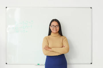 Asian female teacher near blackboard in classroom