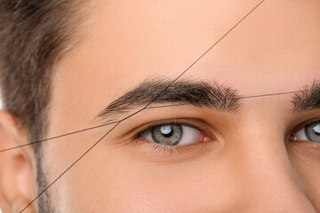 Young man undergoing eyebrow correction procedure, closeup