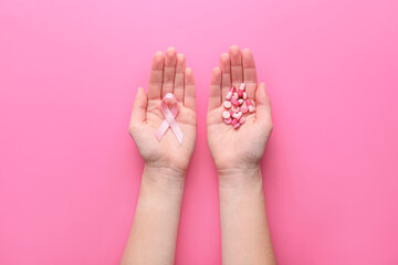Hands with pink ribbon and remedy on color background. Breast cancer awareness concept