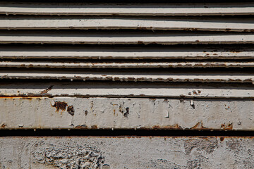 Rusty metal grilles, painted with paint and peeled off from old age, ventilation holes for air ingress in industrial facilities, an electric shield, an opening door
