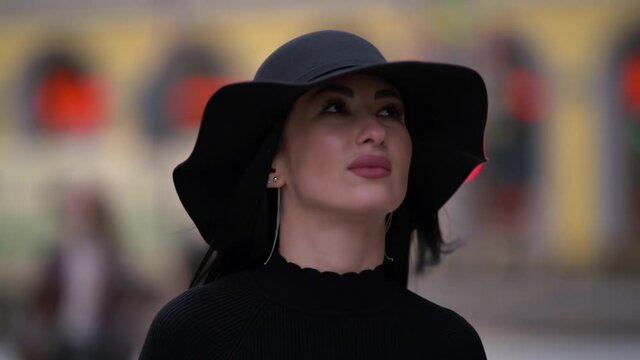 stylish woman in black is walking in city, closeup portrait of sexy lady with hat in movement