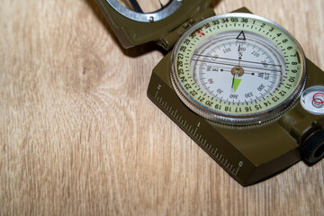 Close-up of a military compass on a wooden surface. Determining the direction of the compass.