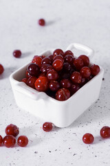 selective focus. fresh cranberry berries in a white ceramic dish. on light background. minimalism. copyspace