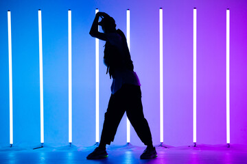 Young breakdancer guy dancing hip-hop in colorful neon background with neon lamps. Breakdance...