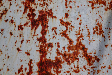 On a rough wall or floor, paint flakes off. Corrosion and rust of metal. Old dilapidated wall.