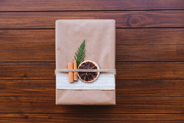 Wrapped present box with natural decorations such as pine cones, fir branch, cinnamon sticks, dry orange slice. Copy space. Zero waste Christmas concept. Plastic free holidays. Sustainable lifestyle.