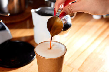 The practice latte art with select focus with coffee. Close up shot hand of barista making freshly latte art in paper cup. How to make latte art