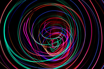 Multi color light painting photography, swirl and curve of blue, green and red light against a black background.