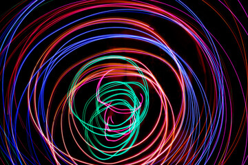 Multi color light painting photography, swirl and curve of blue, green and red light against a black background.