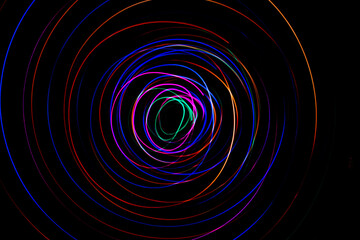 Multi color light painting photography, swirl and curve of blue, green and red light against a black background.