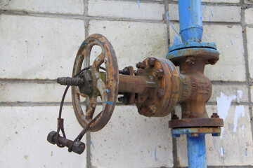 Old damaged and rusty iron oil pipe valve wheel. Metal, pipeline and mechanic concept. An old iron...