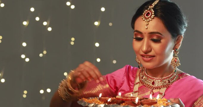 Woman in a saree decorating the plate with diyas	