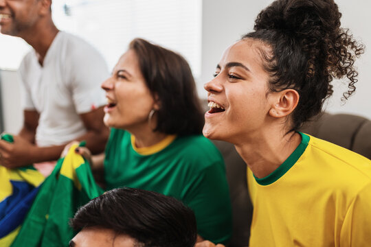 real latin american family watching football on television, celebrating goal of brazil