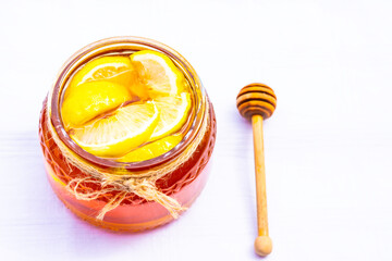 Honey in a glass jar with lemon on white background