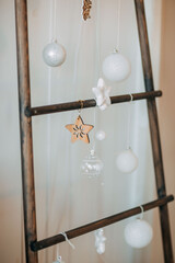 Christmas decorations. Scandinavian decorations with wooden stairs and christmas ornaments on it. Wooden stars and fairy lights on the stairs.