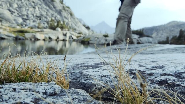 Hiker walks past camera with beautiful landscapes, lake, and mountains in background
