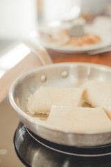 The process of making breakfast: a tortilla with cheese is fried in a pan.