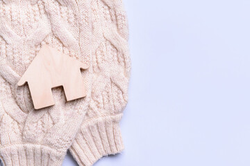 Figure of house and warm sweater on light background. Concept of heating season