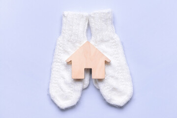 Figure of house and warm mittens on light background. Concept of heating season