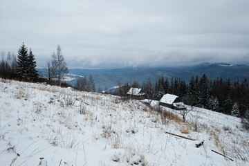 Empty shepherd houses in winter season with background of cloudy overcast sky, Carpathian...