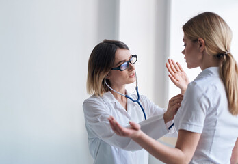 Woman doctor with stethoscope and glasses examines the patient health model