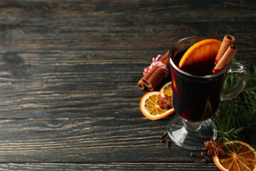 Glass of mulled wine and ingredients on wooden table