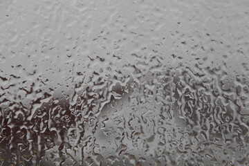 Ice drops on glass surface on blurred house roof backdrop, abstract  autumn texture for background