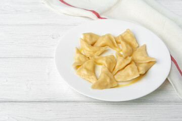 Russian dumplings on white plate on white wooden table