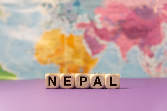 The word Nepal written with wooden dices in front of a purple background and a geographic map