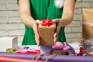 Female hands holding a small gift box wrapped in packing paper. To give and receive gifts from loved ones for christmas, valentines, birthday.