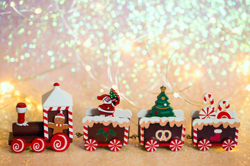 Christmas train on a shiny background. Toy wooden train with gifts, Santa, parcels and Christmas tree close-up.