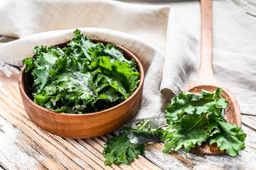 Fresh green superfood kale leaves in wooden bowl. Organic Vegetarian food. White background. Top view