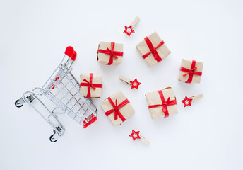 Top view on shopping cart with gifts and christmas decorations scattered on white background. - 393507513