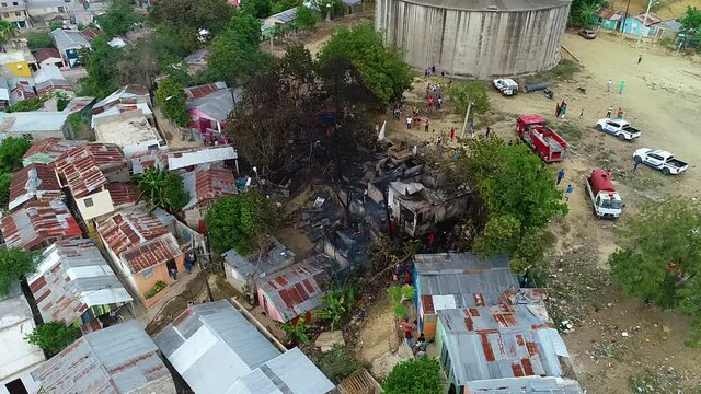 Aerial view around firefighters and people at a burnt building fire, in the slums of Mexico city, Central America - orbit, drone shot
