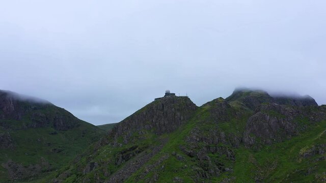 Aerial view of a Observatory on the top of a mountain, near the Sto , in Vesteralen islands, foggy, overcast day, in Norway - orbit, drone shot