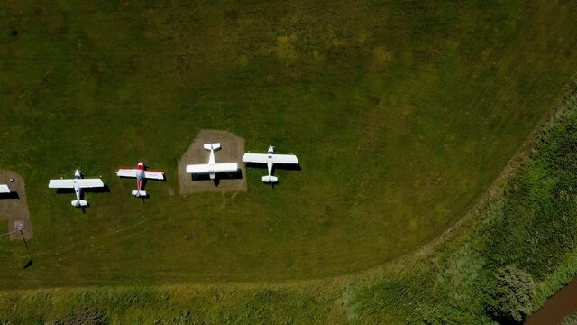 Aerial view above small airplanes, at a microlight aircraft airport, in Europe- descending, overhead, drone shot