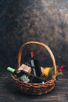 Bottles of red and white wine in Christmas gift basket. Mulled wine with oranges, cups and fir-tree ornaments in box. Top view