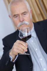 elderly man holding a glass of wine