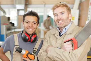 portrait of carpenter with apprentice holding tools